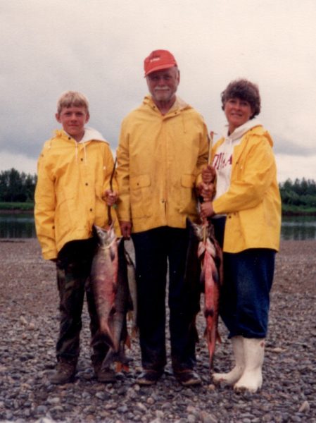 family holding sockeye salmon on beach